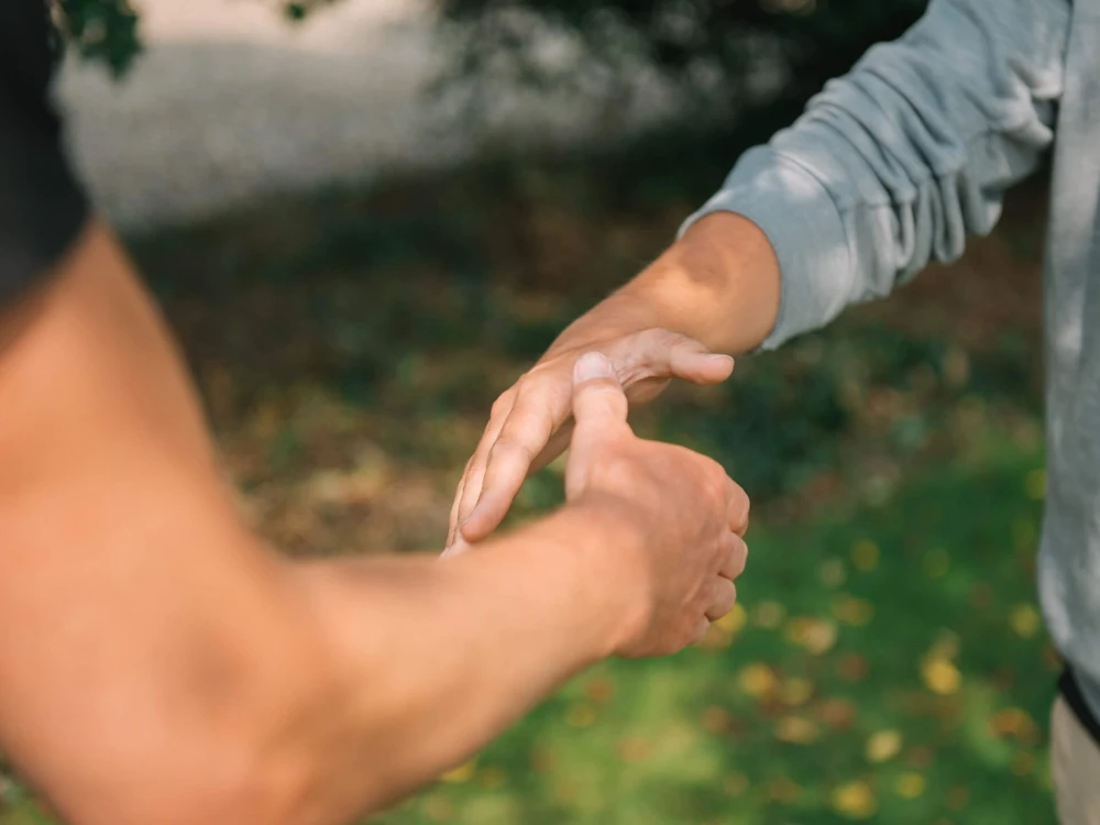 Zwei Personen führen einen Handschlag im Freien durch
