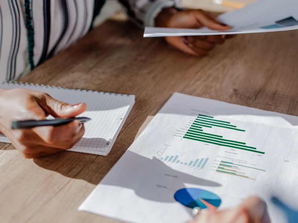 People analyzing business data at a table with charts and notebooks