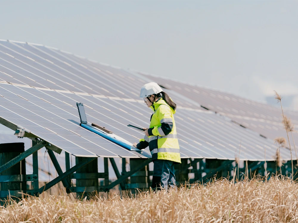 Ingenieurin in Schutzausrüstung inspiziert Solarpaneele auf einem Feld