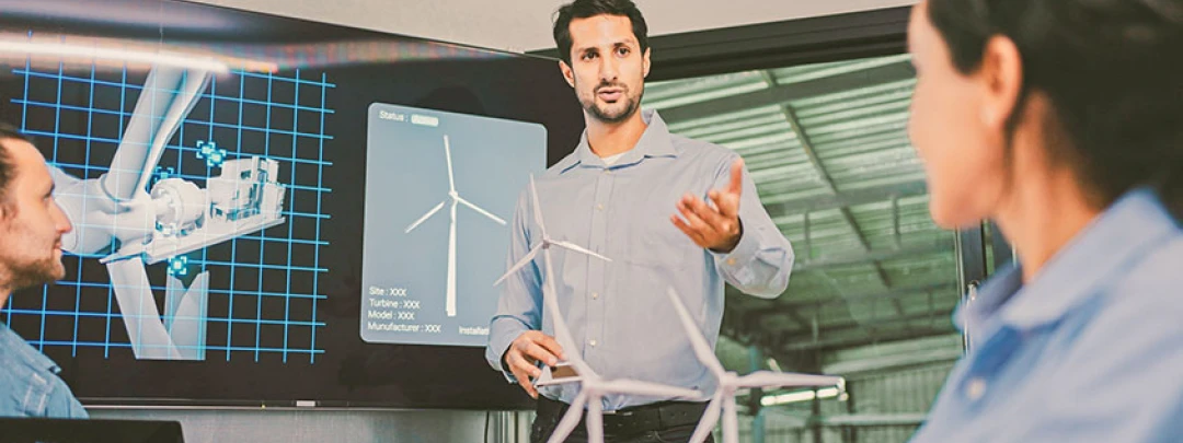 Man presenting wind turbine designs on a screen to colleagues in an office