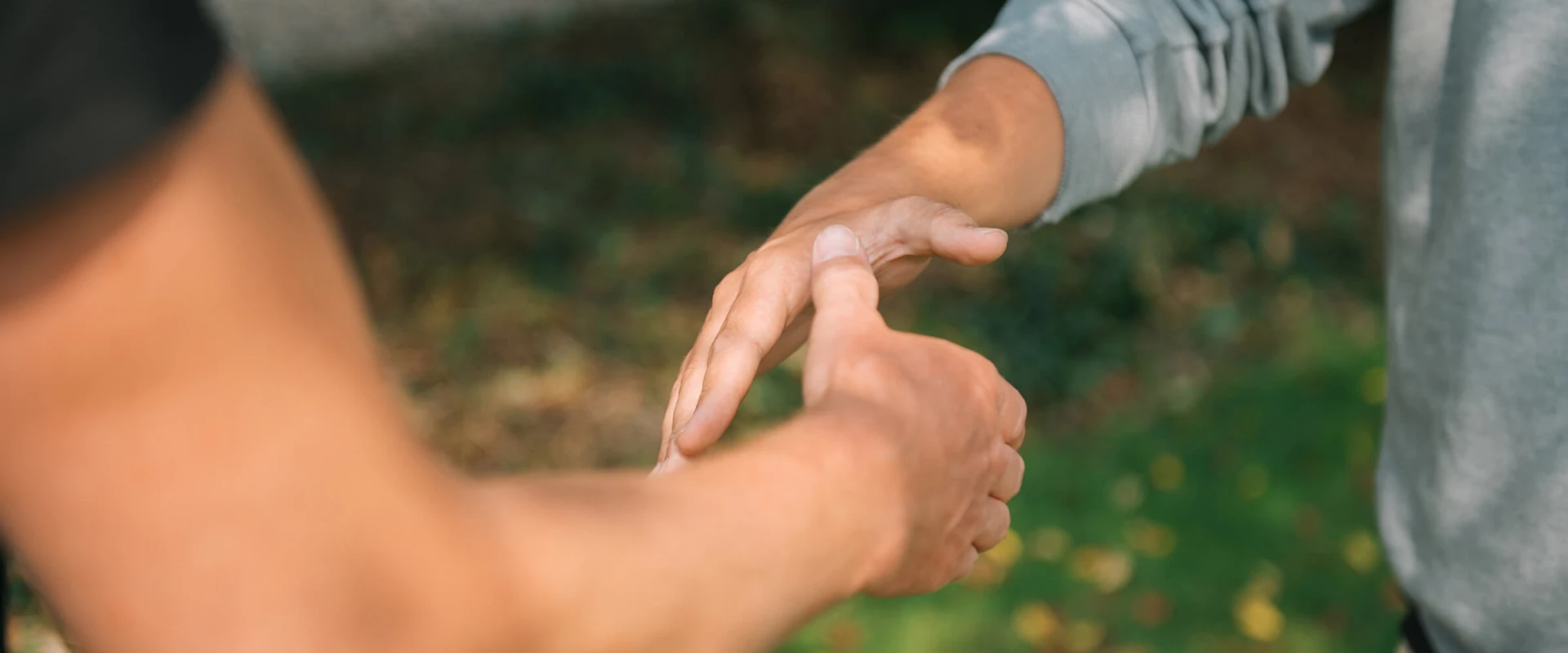 Zwei Personen halten sich im Freien an den Händen