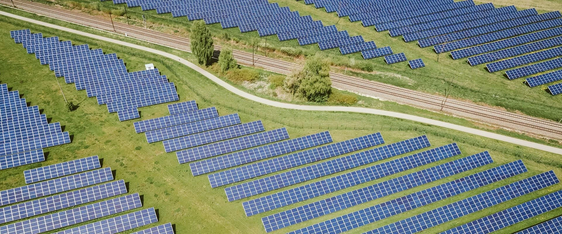 Luftaufnahme eines großen Solarparks mit zahlreichen Photovoltaik-Modulen, die in Reihen angeordnet sind