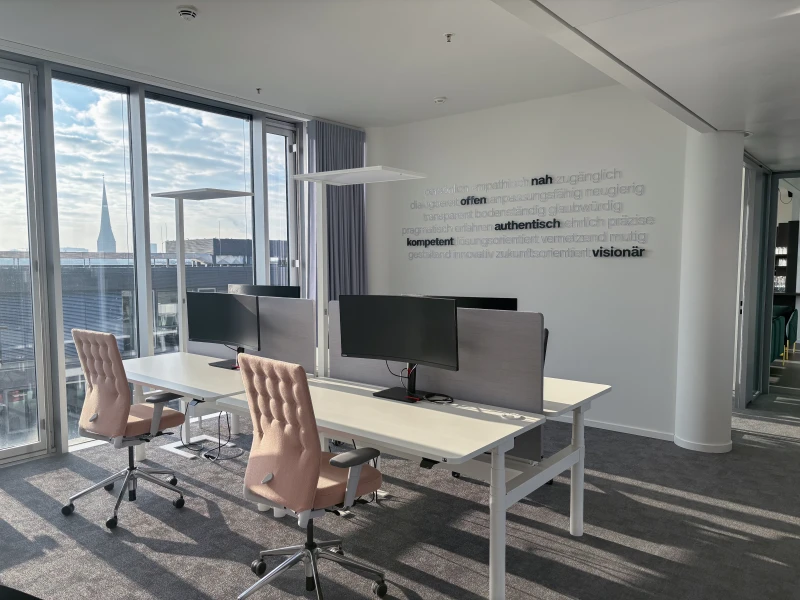 Modern office with two workstations, large windows, and a city view