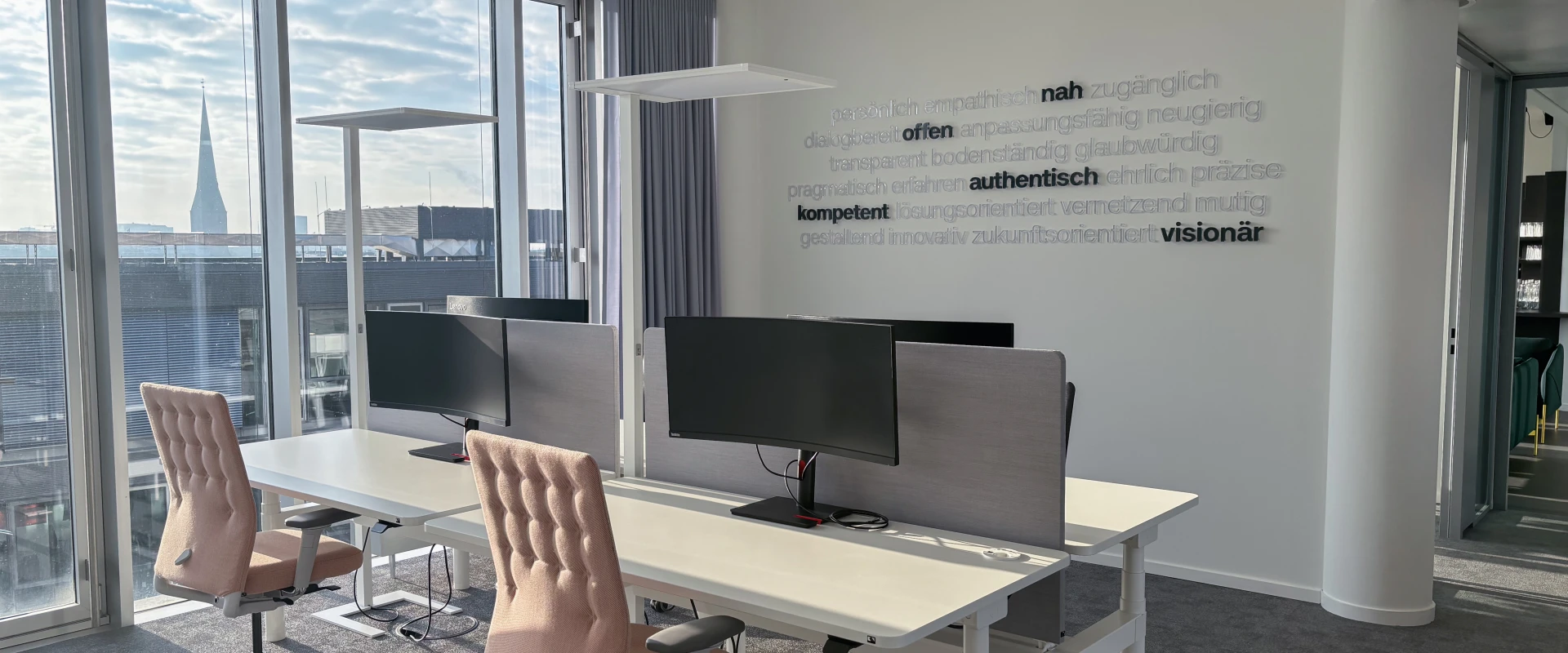 Modern office with two workstations, large windows, and a city view