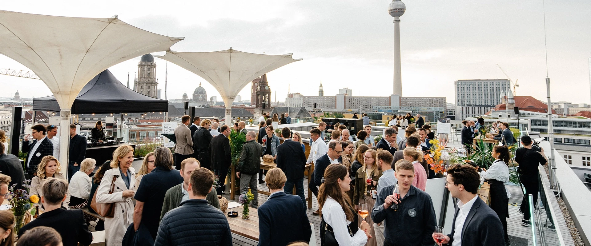 People at a social event on a rooftop terrace overlooking the Berlin skyline with the TV Tower