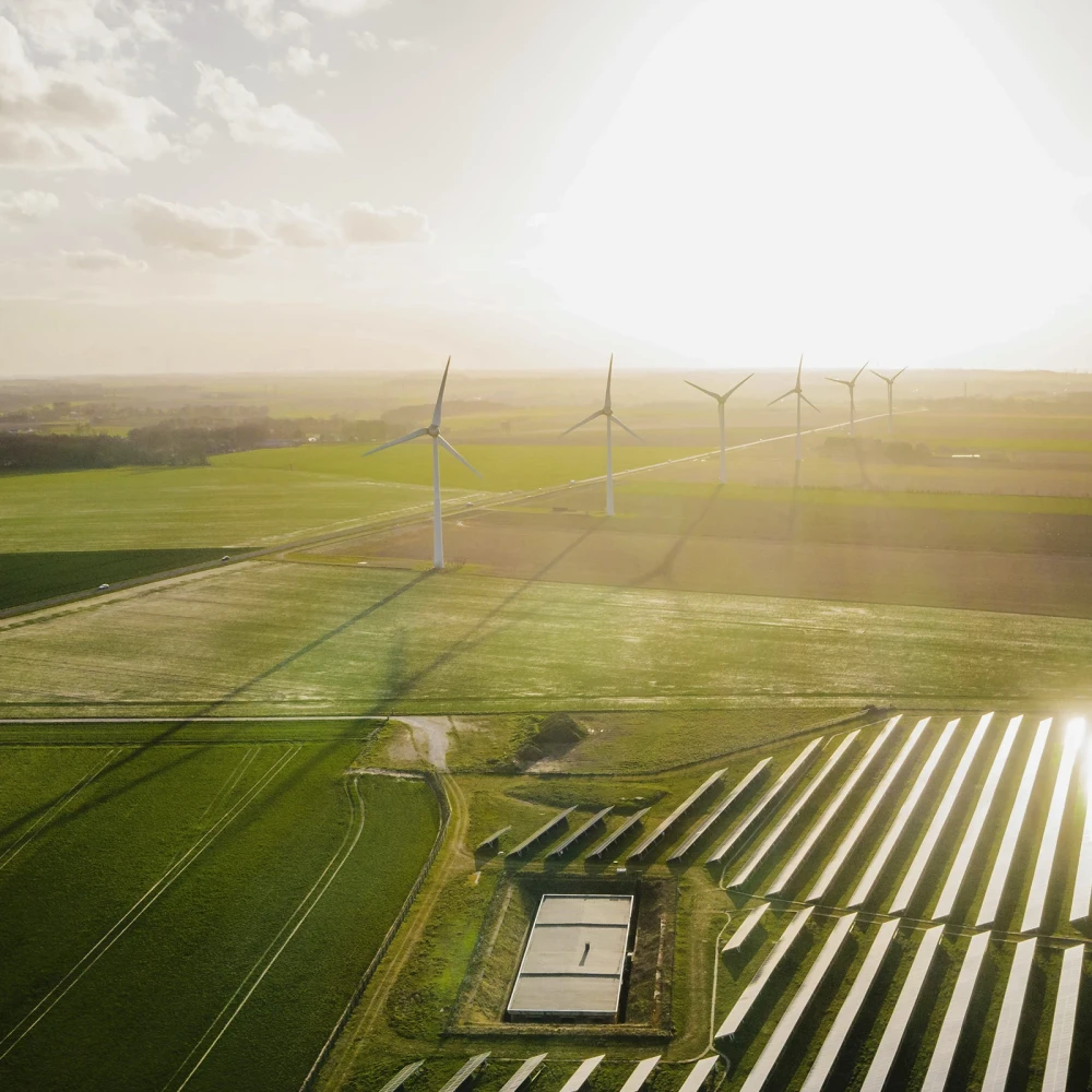 Aerial view of wind turbines and solar panels in a rural area at sunset
