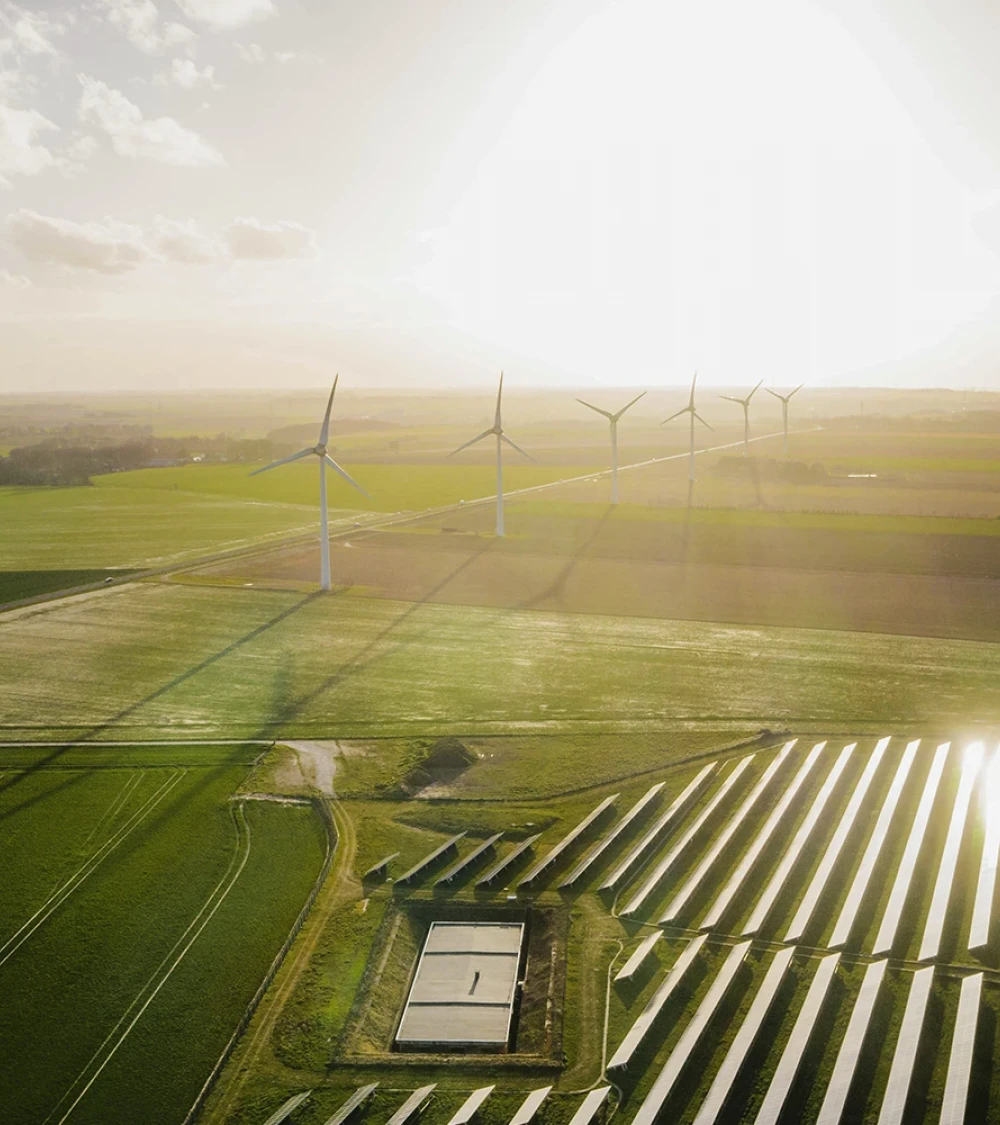 Aerial view of wind turbines and solar panels on a field at sunset