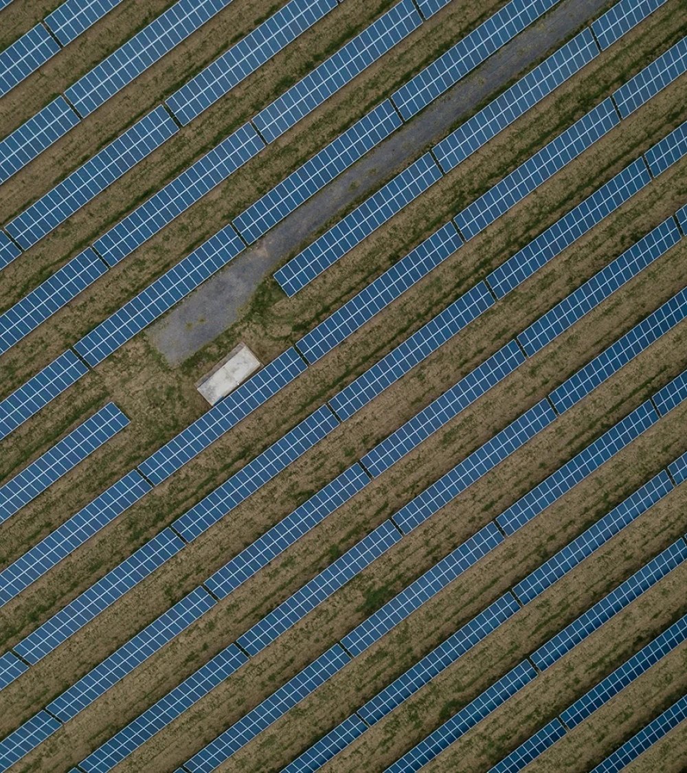 Aerial view of a large solar farm with evenly arranged solar panels and a small grassy area